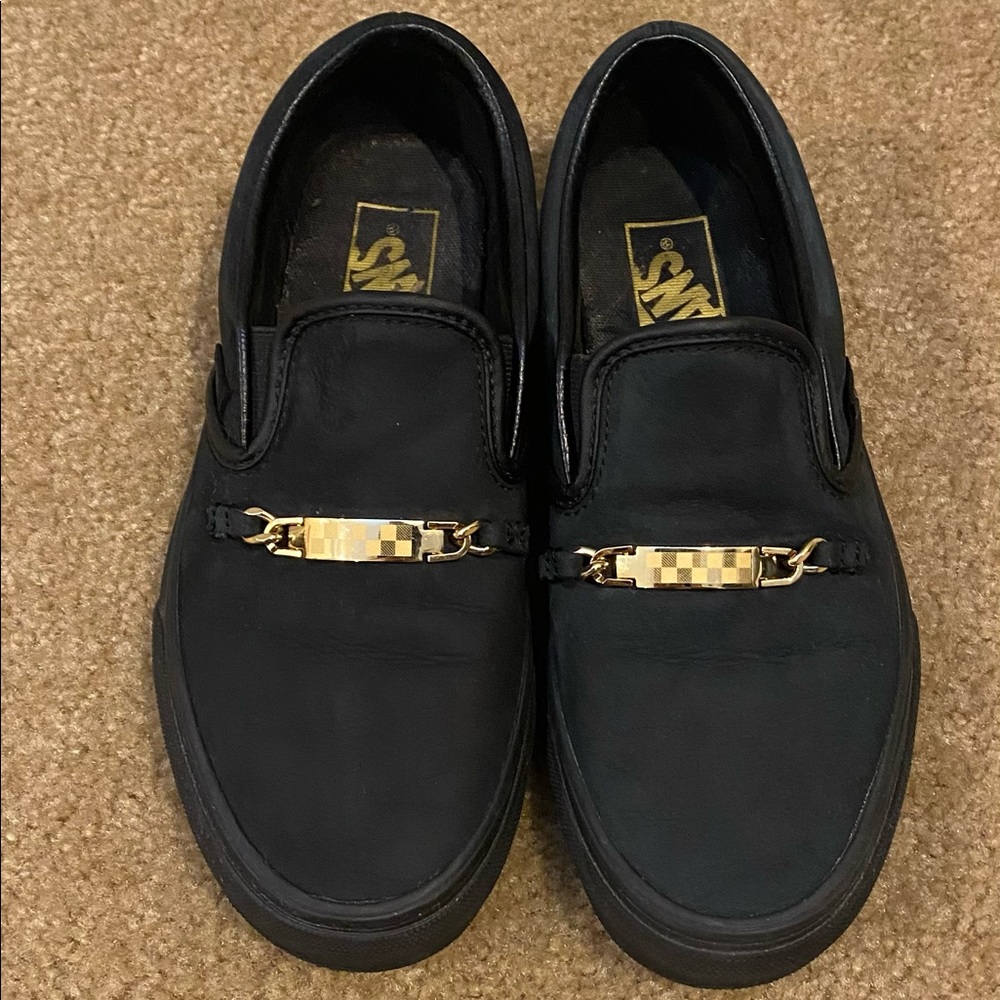 Classic slip on Vans with checked gold accessory.
